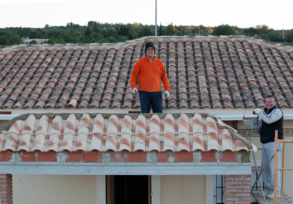 Roofers restoring a terracotta tile roof