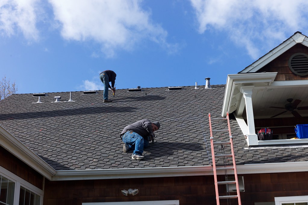 Roofers repairing a shingle roof