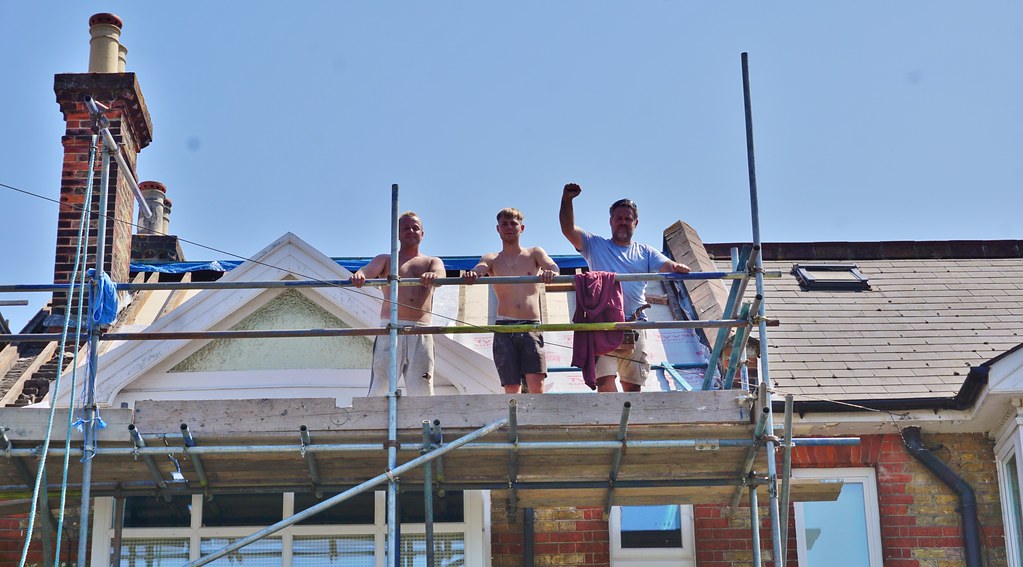 Roofing crew on scaffold at a gable roof restoration